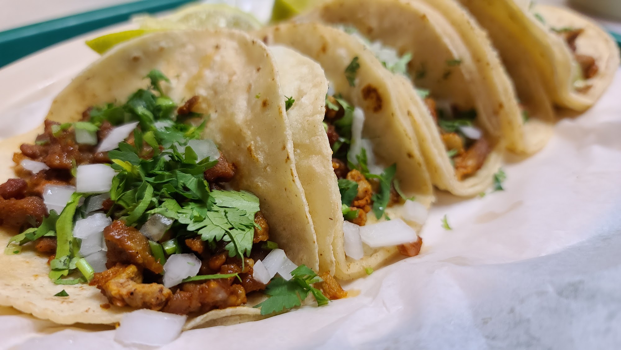 Close-up of trompo tacos with cilantro and onion on parchment
